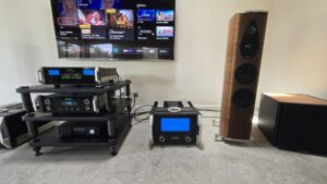 Système hi-fi haut de gamme McIntosh (VU-mètres bleus) et enceinte colonne en finition bois — installation Design Audio à domicile