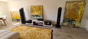 Système hi-fi haut de gamme intégré dans un salon décoré : enceintes colonne noires et électronique haut de gamme parmi des œuvres d'art — installation Design Audio à domicile